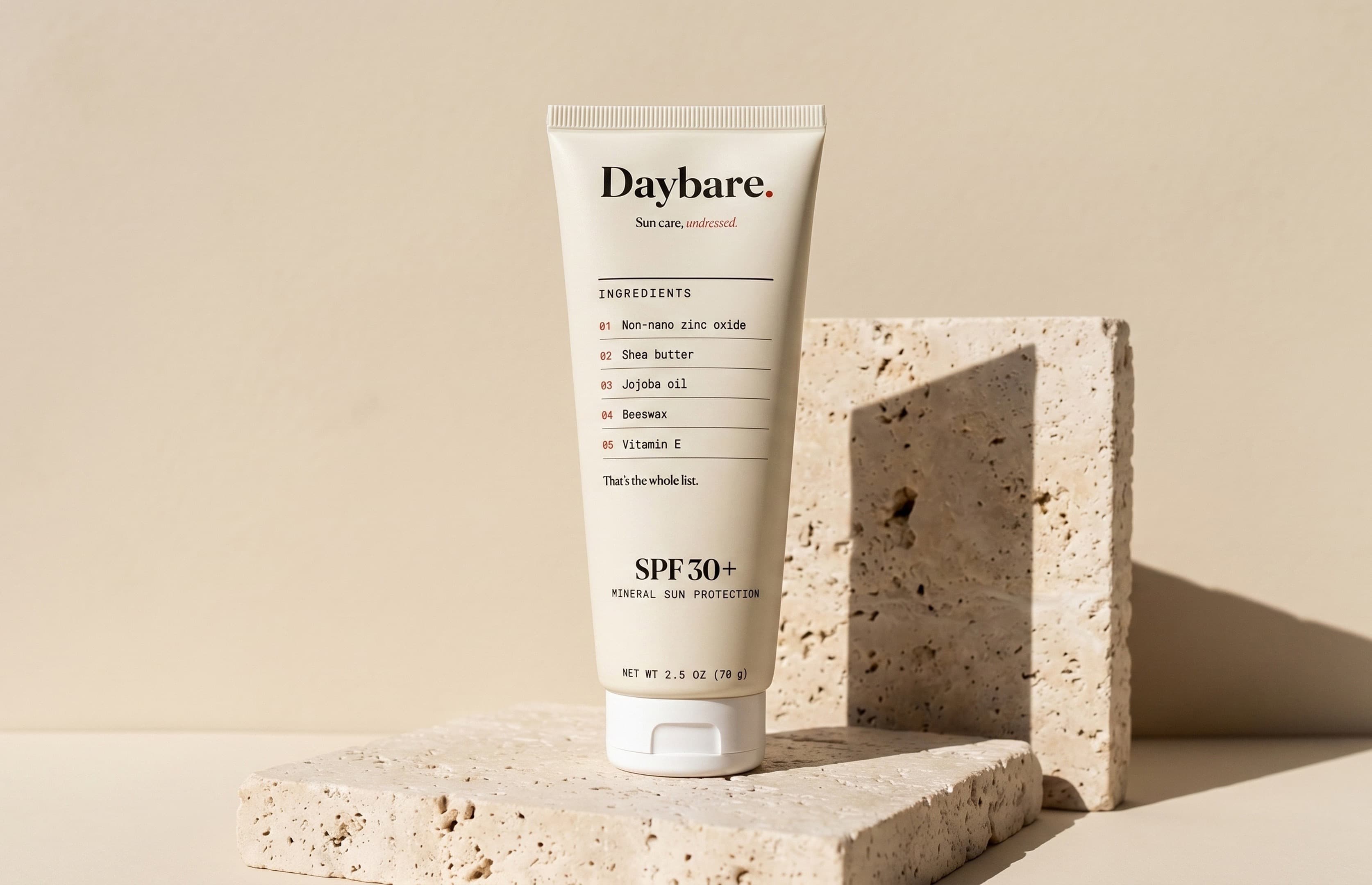 Daybare tube standing on travertine stone in hard sunlight, ingredient label facing forward